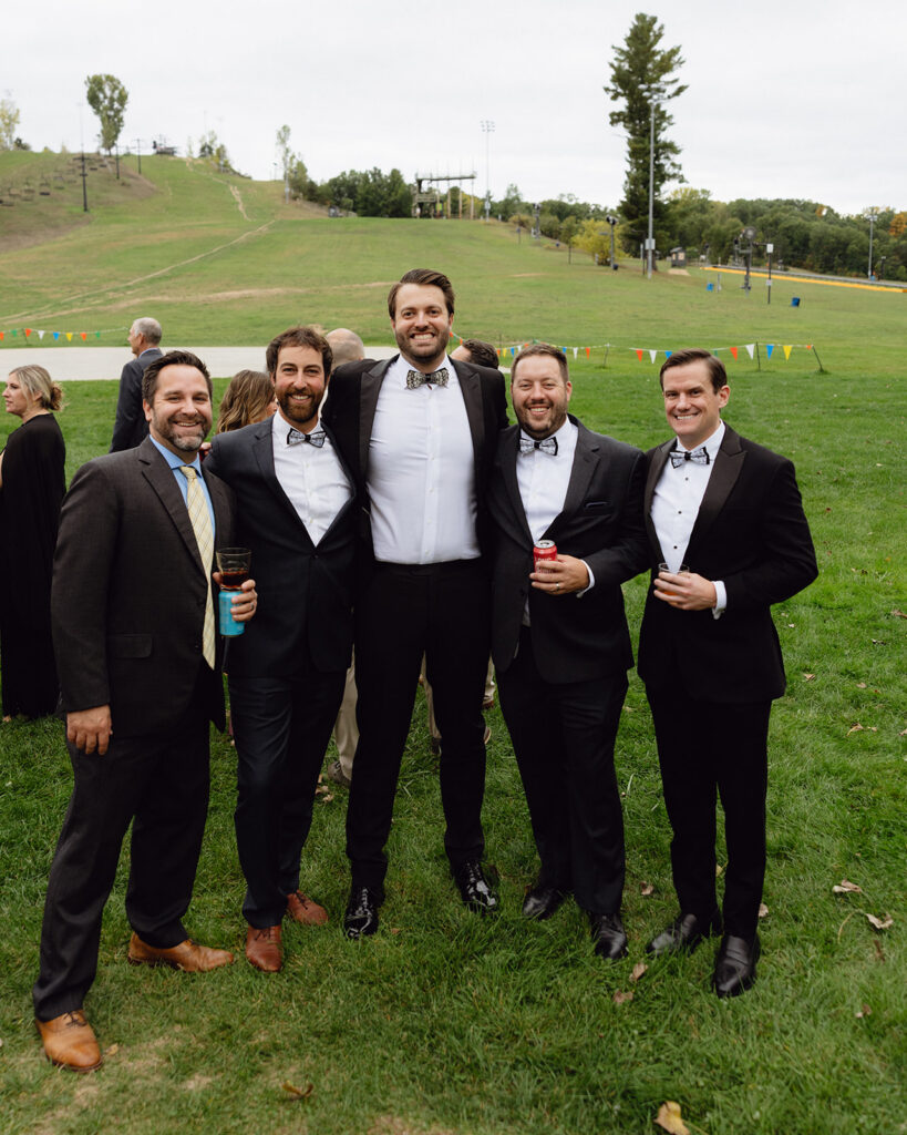 Groom posing with guests outdoors during his Michigan wedding near Grand Rapids. 