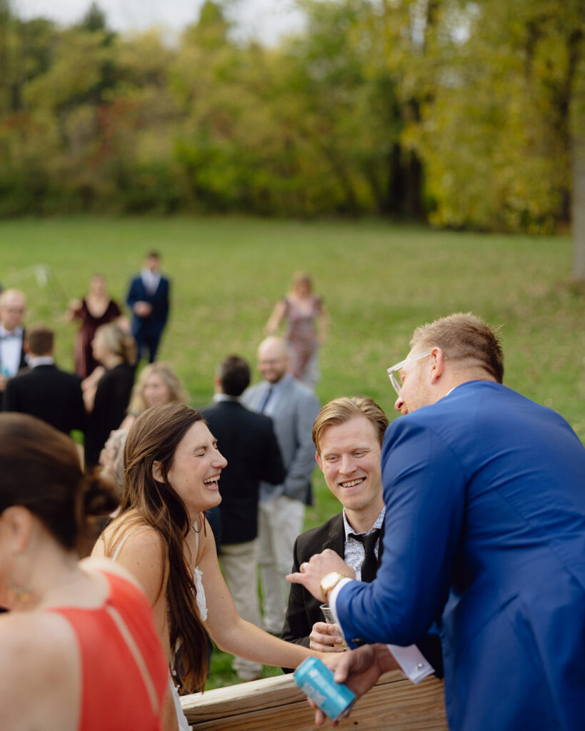 Bride laughing as she talks to guests outdoors. 