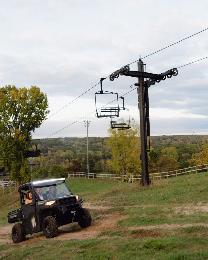 Bride and groom riding a side-by-side up a hill at Michigan documentary wedding.