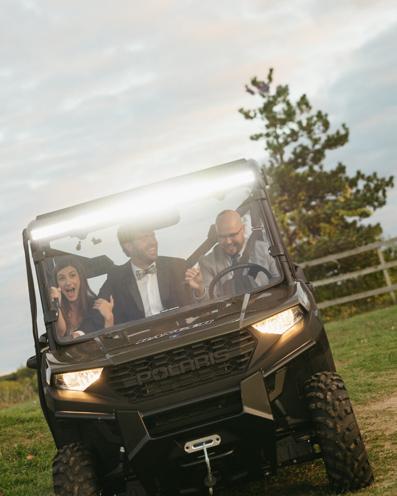 Bride and groom riding a side-by-side up a hill at Michigan documentary wedding.