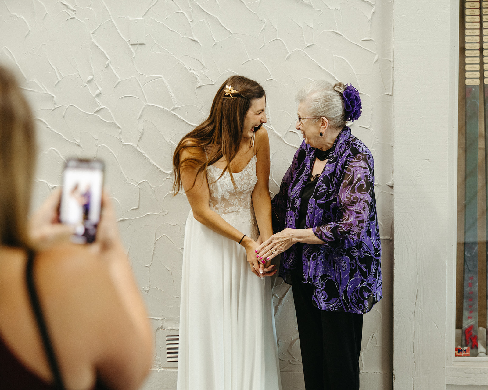 Bride laughing and holding hands with a guest.