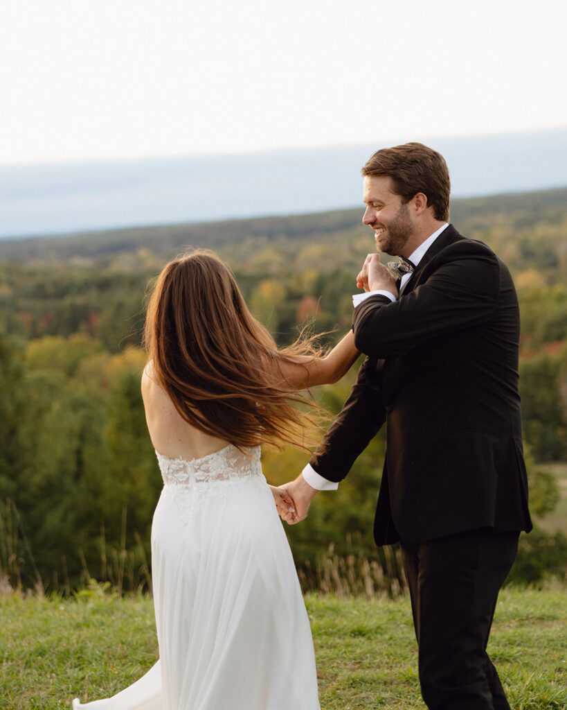 Groom and bride dancing while overlooking scenic Michigan landscape during sunset.