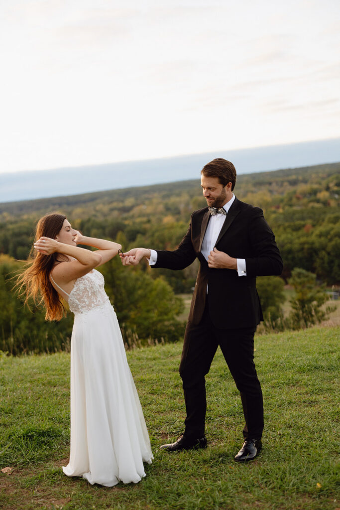 Documentary style Michigan wedding photo of a bride and groom on top of a hill at sunset.