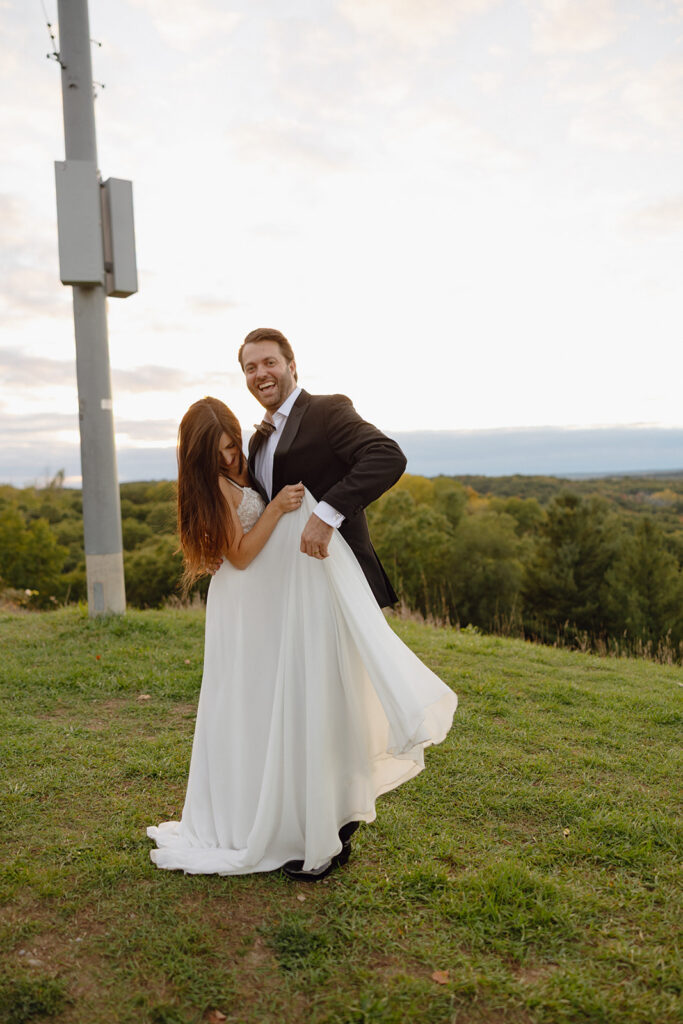 Bride and groom having fun during sunset as they explore outdoors together.