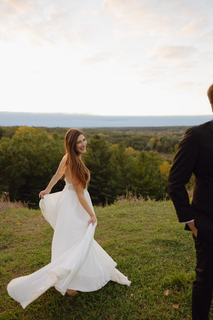 Bride and groom playing and spinning during candid sunset wedding photos.