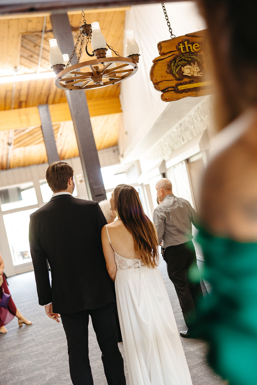 Bride and groom walking together through the reception space as guests arrive around them.