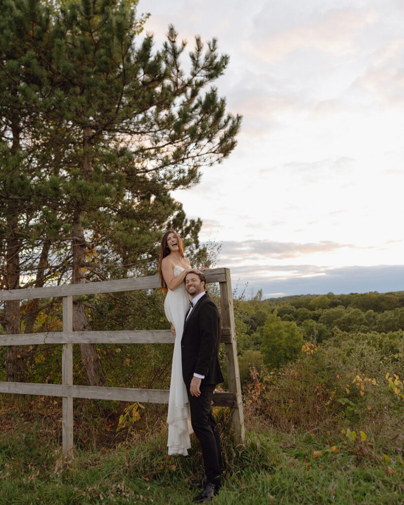 Couple standing by a fence during their Michigan wedding photos near Grand Rapids.