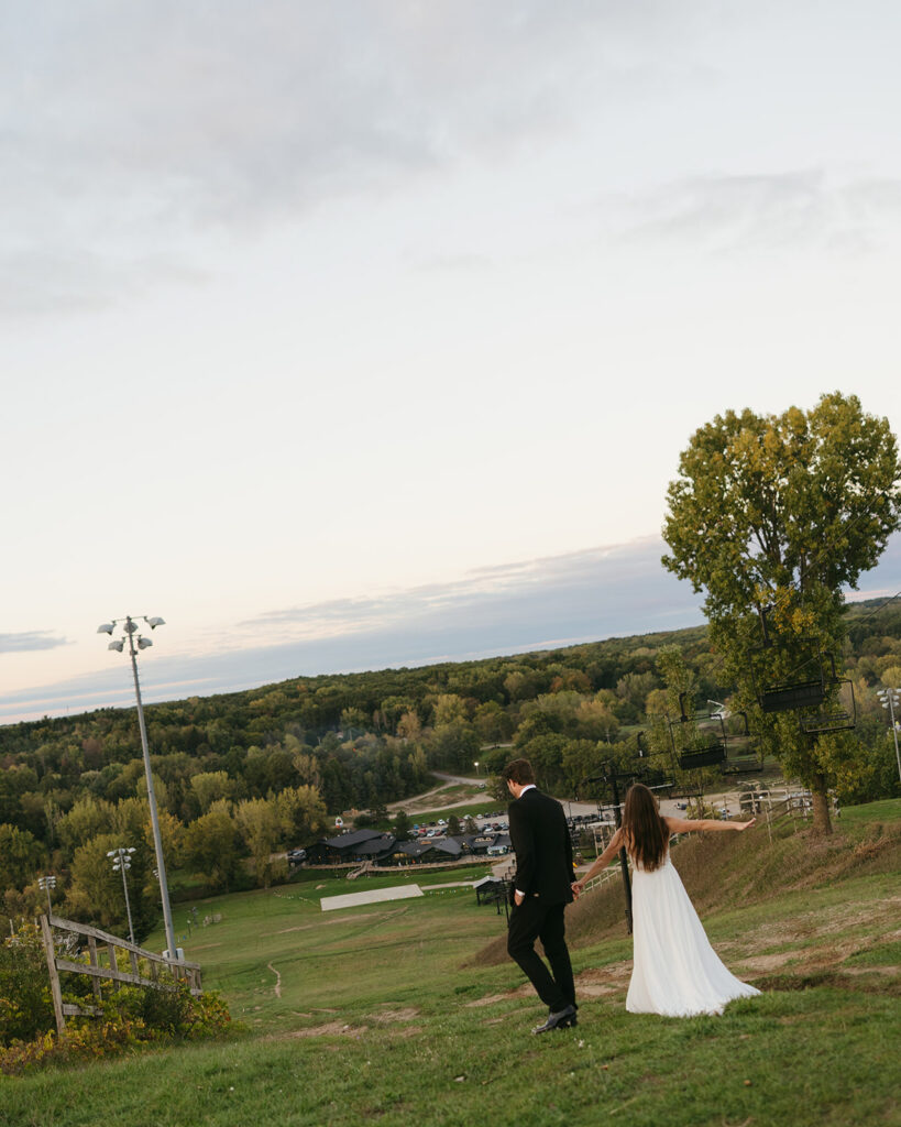 Bride and groom walking back down a hill together near Grand Rapids, Michigan.