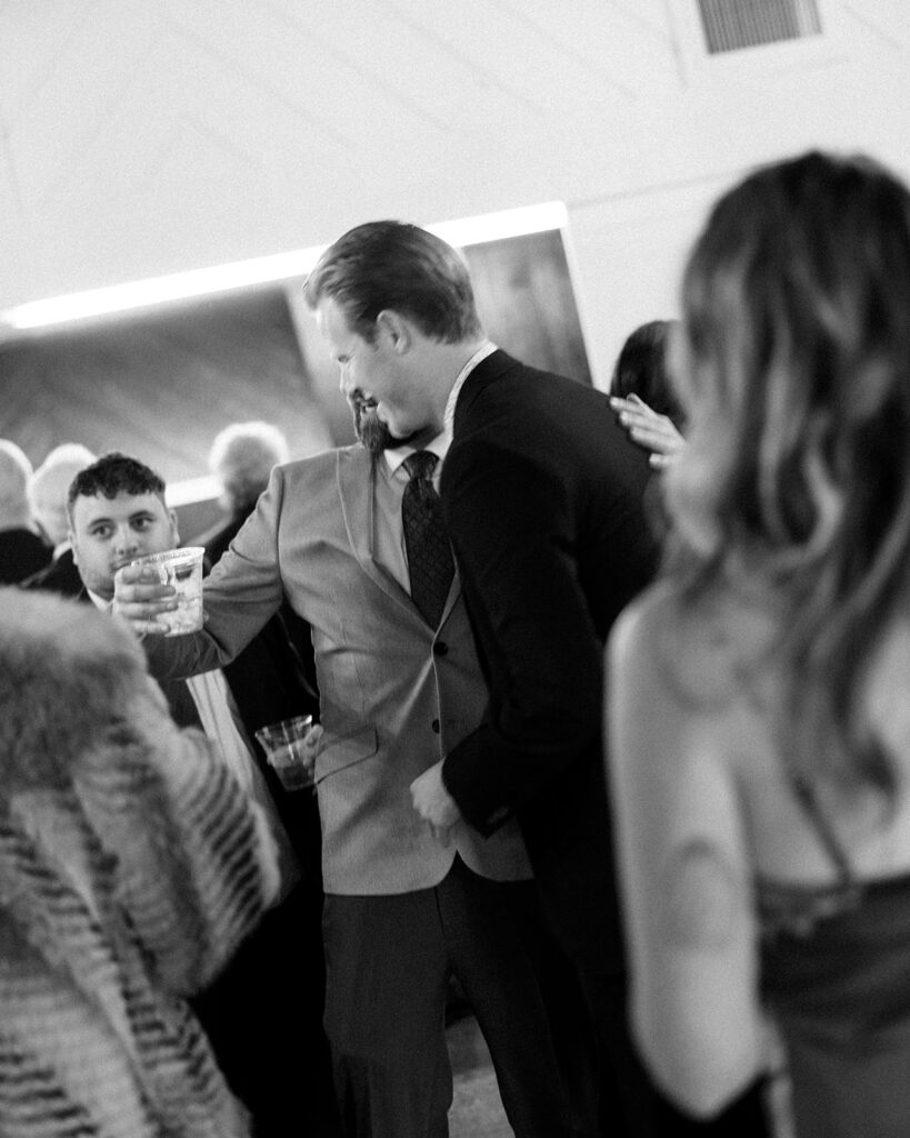 Black and white photo of guests hugging and mingling together from a Michigan wedding near Grand Rapids. 