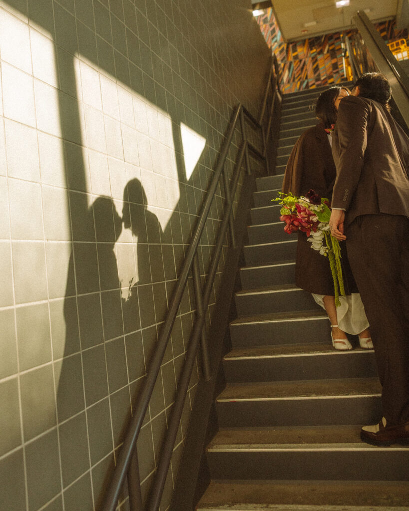 Couple kissing on staircase with their shadows showing on the wall during a downtown Detroit elopement.