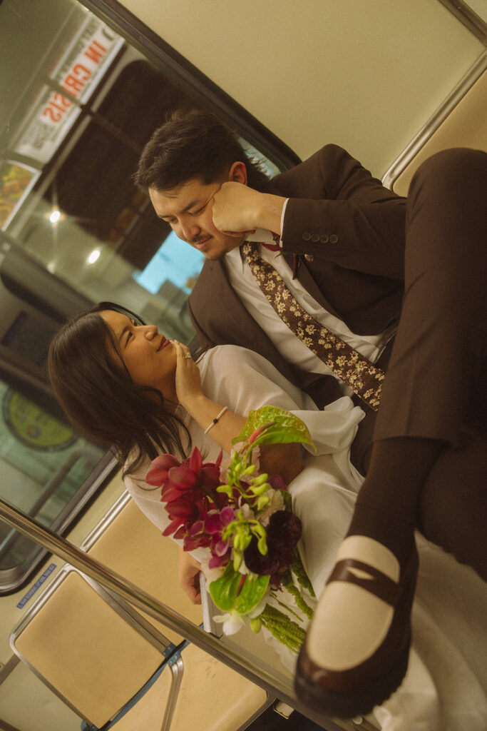 Bride and groom sitting together on Detroit People Mover during downtown Detroit elopement with bouquet in lap.