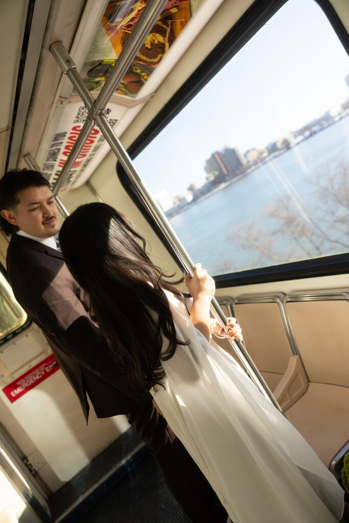 Bride and groom standing by window on Detroit People Mover overlooking skyline during downtown Detroit elopement.