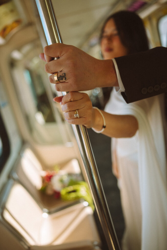 Close-up of bride and groom holding onto pole inside People Mover during downtown Detroit elopement.