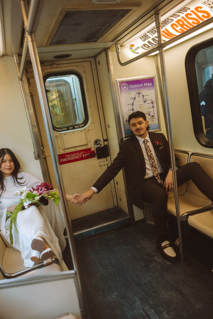 Bride and groom sitting across from each other holding hands on Detroit People Mover during downtown Detroit elopement.