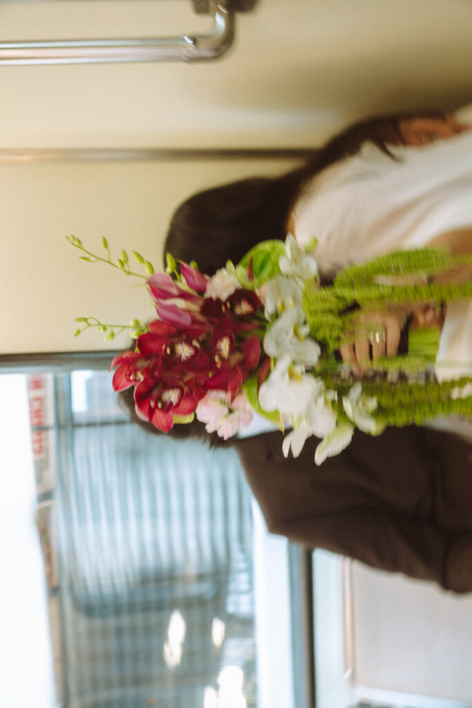 Bride and groom kissing behind the brides bouquet on the Detroit People Mover.