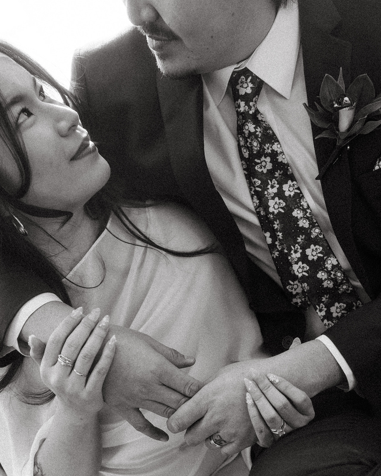 Close-up of black and white portrait of a bride and groom holding hands with soft light during downtown Detroit elopement.