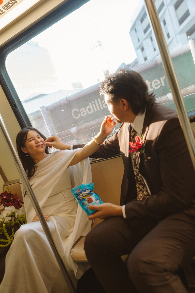 Bride and groom feeding each other Nerd Clusters candy on Detroit People Mover during downtown Detroit elopement.