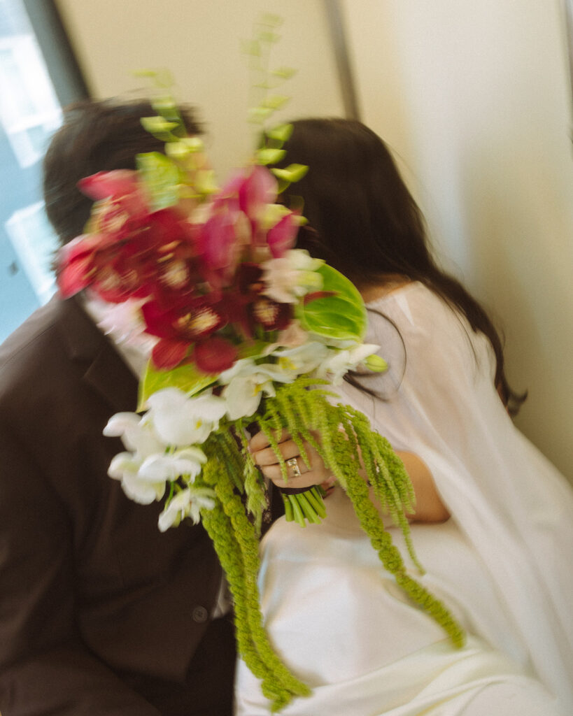 Close up shot of a bride and groom kissing behind a bouquet as they ride the People Mover for their Downtown Detroit elopement photos.