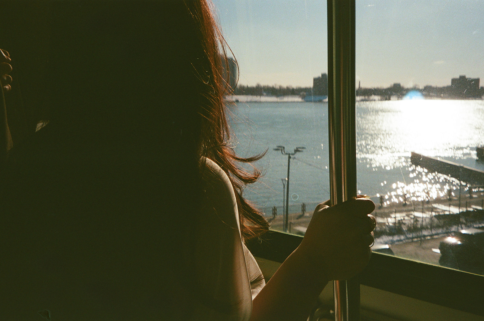 Bride looking out window on Detroit People Mover during downtown Detroit elopement film photo with water view and light leaks.