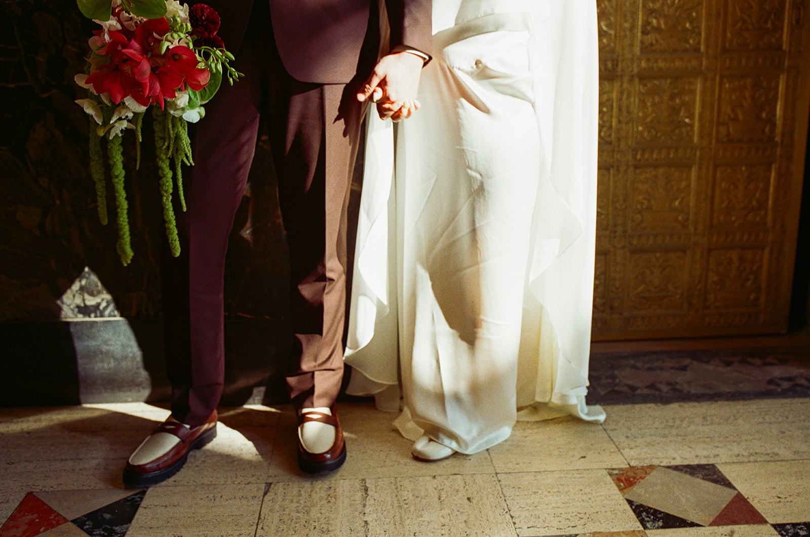 Bride and groom holding hands in golden light during Fisher Building elopement film photo with soft shadows.