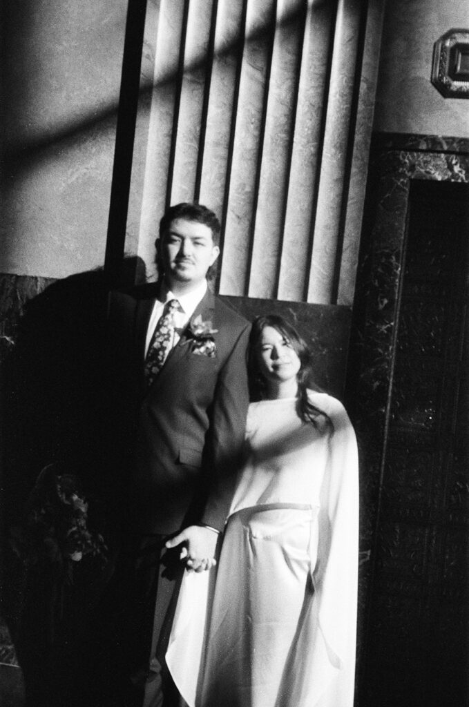 Bride and groom leaning together in doorway during Fisher Building elopement film photo with vintage feel.