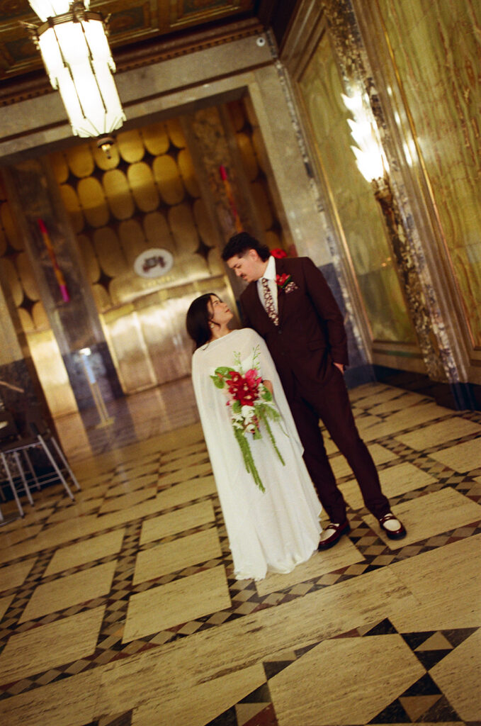 Bride and groom standing together in marble hallway during Fisher Building elopement film photo with cinematic blur.