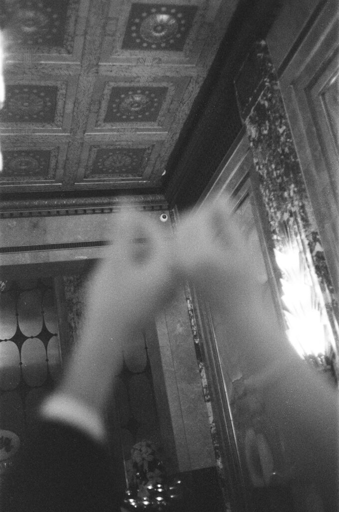 Black and white photo of a bride and groom holding their rings up at Fisher Building captured on film.