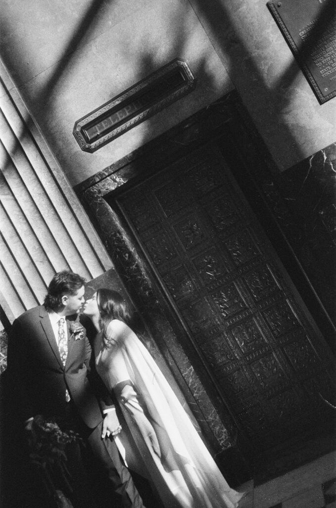 Bride and groom kissing in dramatic light during Fisher Building elopement film photo in black and white.
