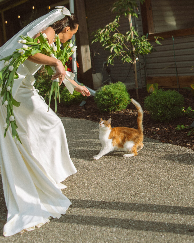Bride petting her cat outdoors.