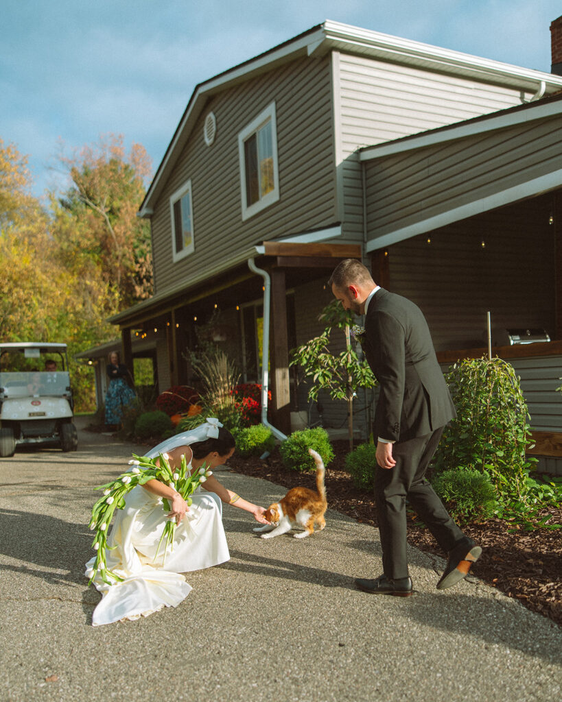Bride leaning down to pet her orange cat.