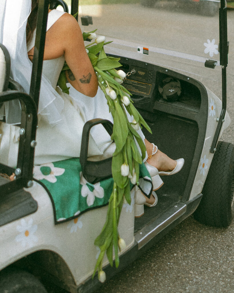 Bride sitting in a gold cart with her bouquet.