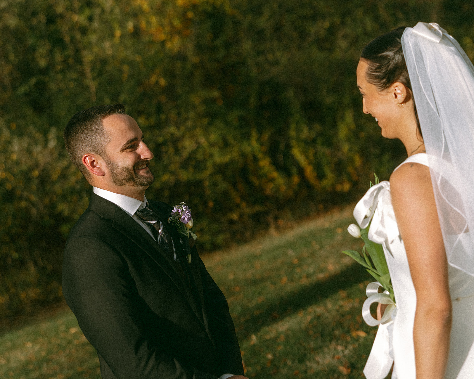 Bride and groom smiling at one another during their first look.