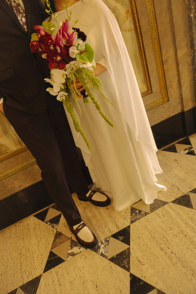 Close up photo of a bride and groom posing against a wall.