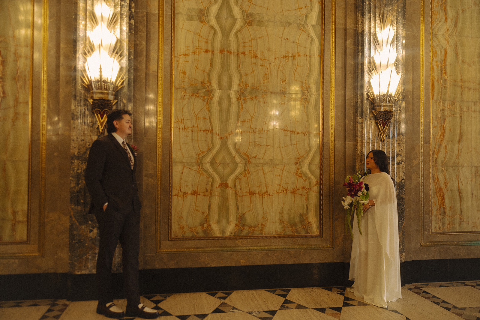 Bride and groom standing apart in grand hallway during Fisher Building elopement in Detroit.
