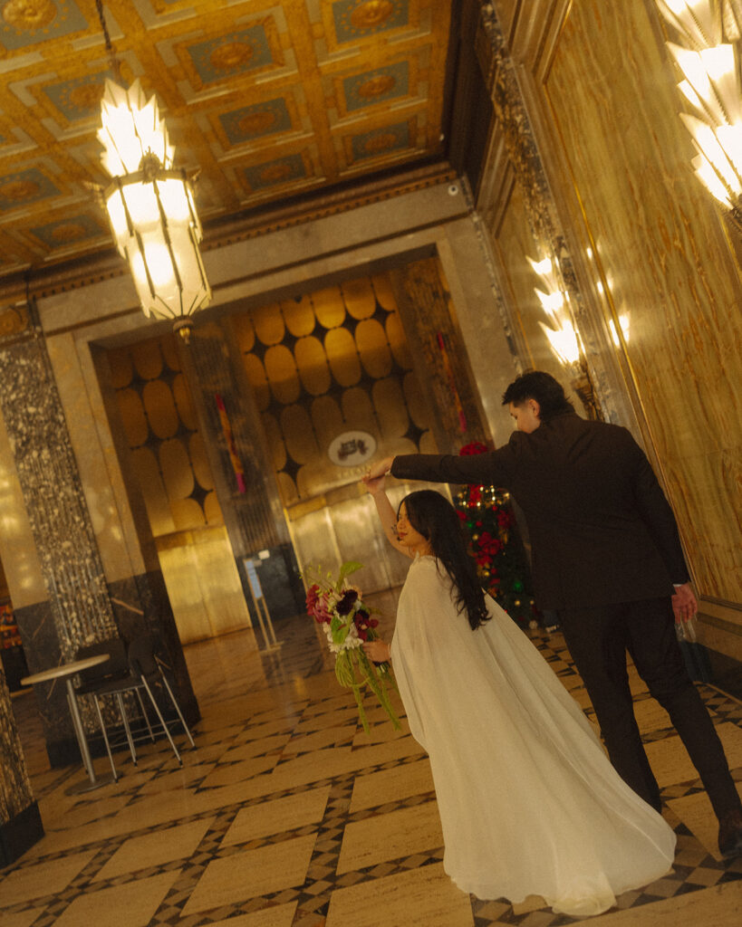 Bride and groom dancing together in fisher building elopement with ornate ceilings and warm lighting.