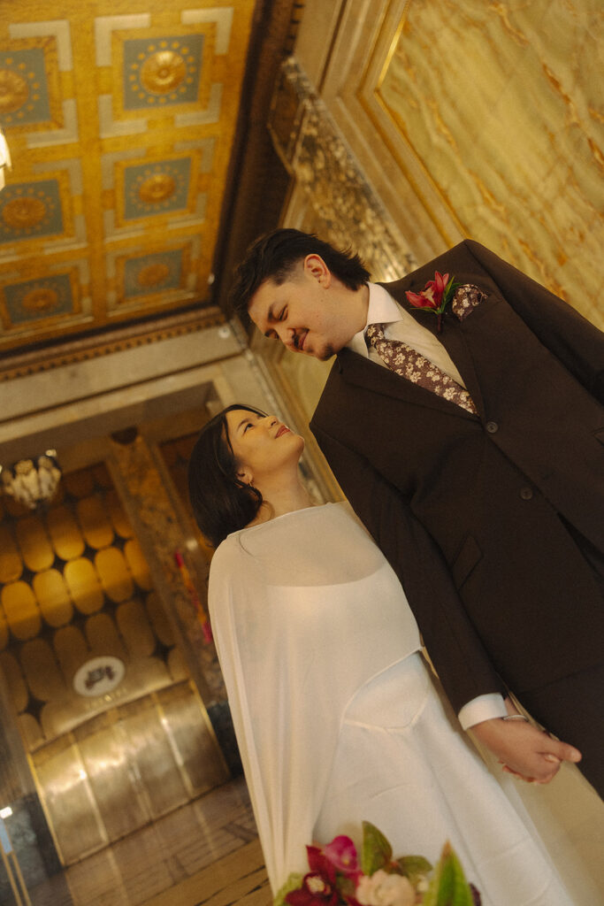 Bride and groom walking hand in hand during Fisher Building elopement with dramatic shadows and architecture.
