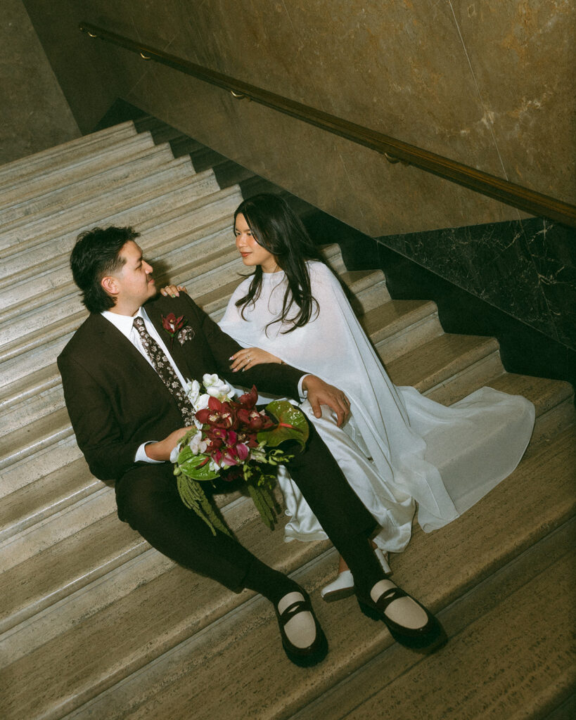 Bride and groom sitting on staircase during Fisher Building elopement.
