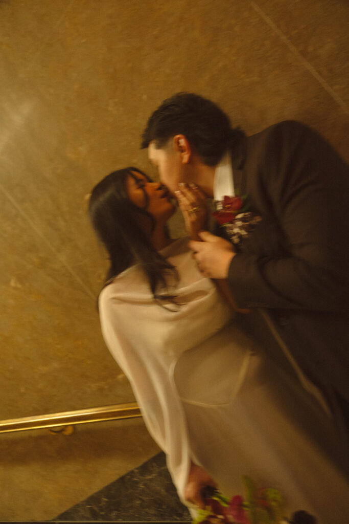 Bride and groom kissing on staircase during Fisher Building elopement in Detroit.