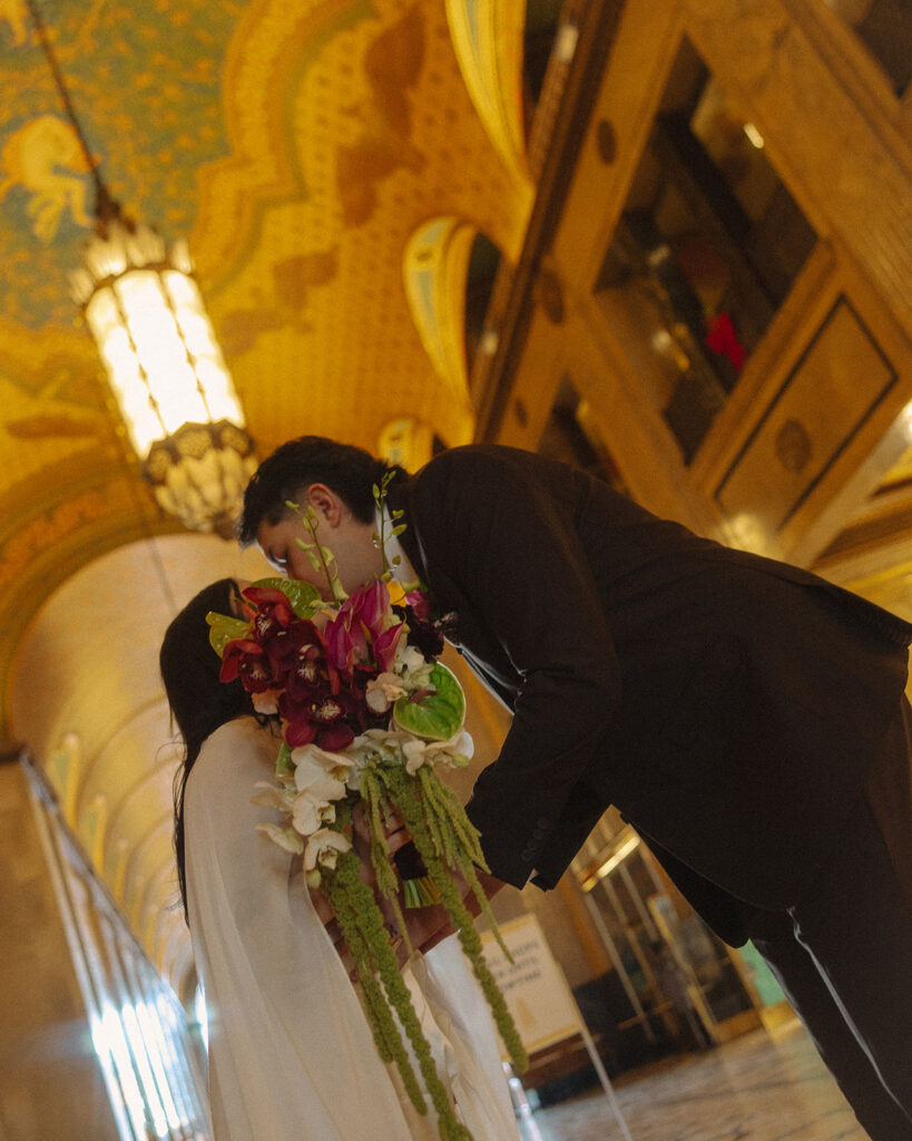 Bride and groom kissing behind a bouquet at Fisher Building in Detroit, Michigan.