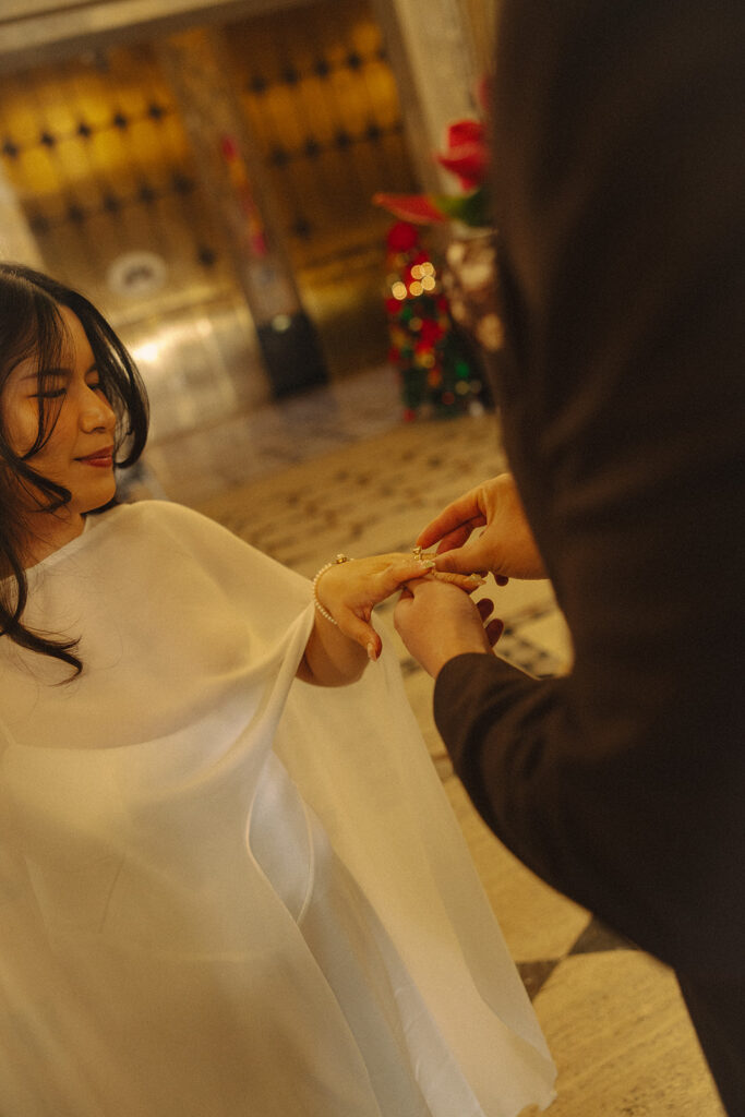 Groom putting a ring on his brides finger during their Fisher Building Detroit elopement.