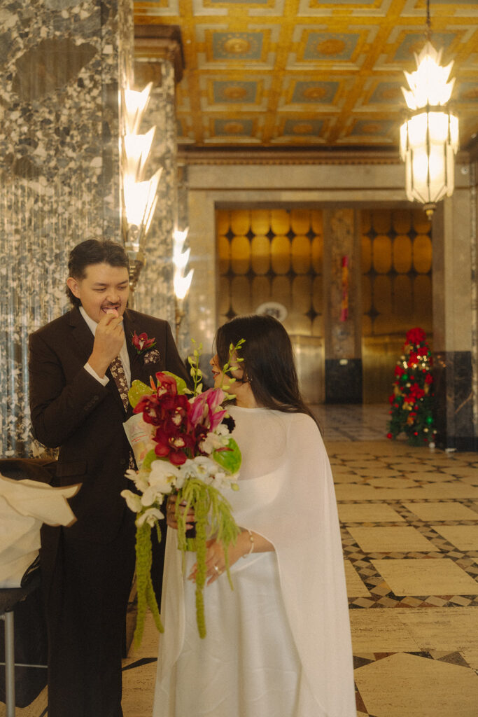 Bride watching the groom eat a snack during their Fisher Building elopement in Detroit.