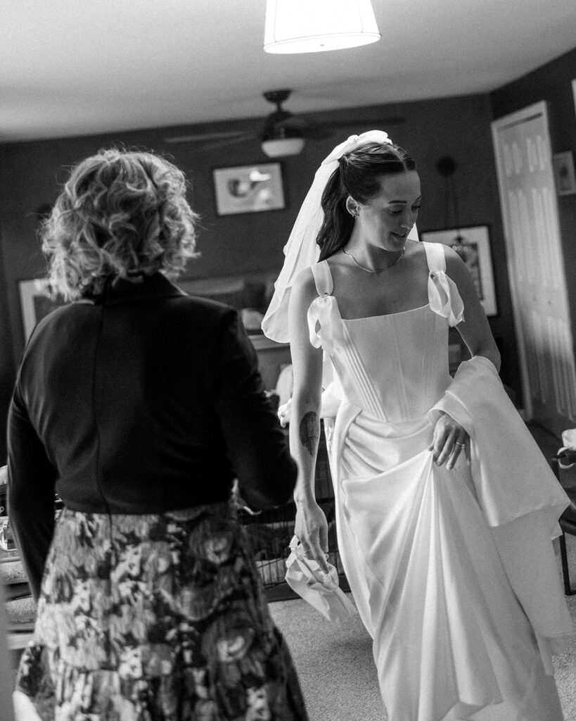 Black and white candid photo of a bride and groom mother as she gets ready for her wedding.