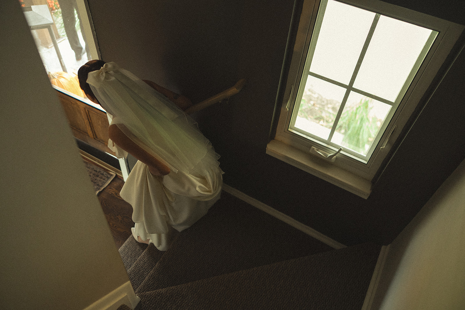 Cinematic style wedding photo of a bride walking down the stairs of her home.