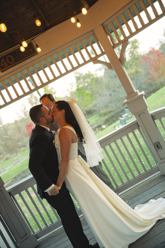 Bride and groom sharing a kiss under pavilion lights during a Clarkston Michigan wedding ceremony.