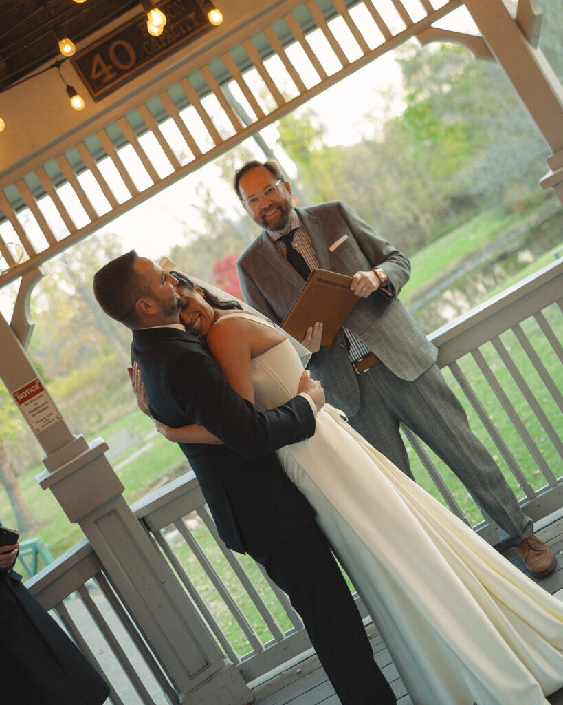 Bride and groom hugging under pavilion lights during a Clarkston Michigan wedding ceremony.