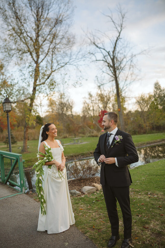 Bride and groom smiling at each other during their outdoor fall portraits.