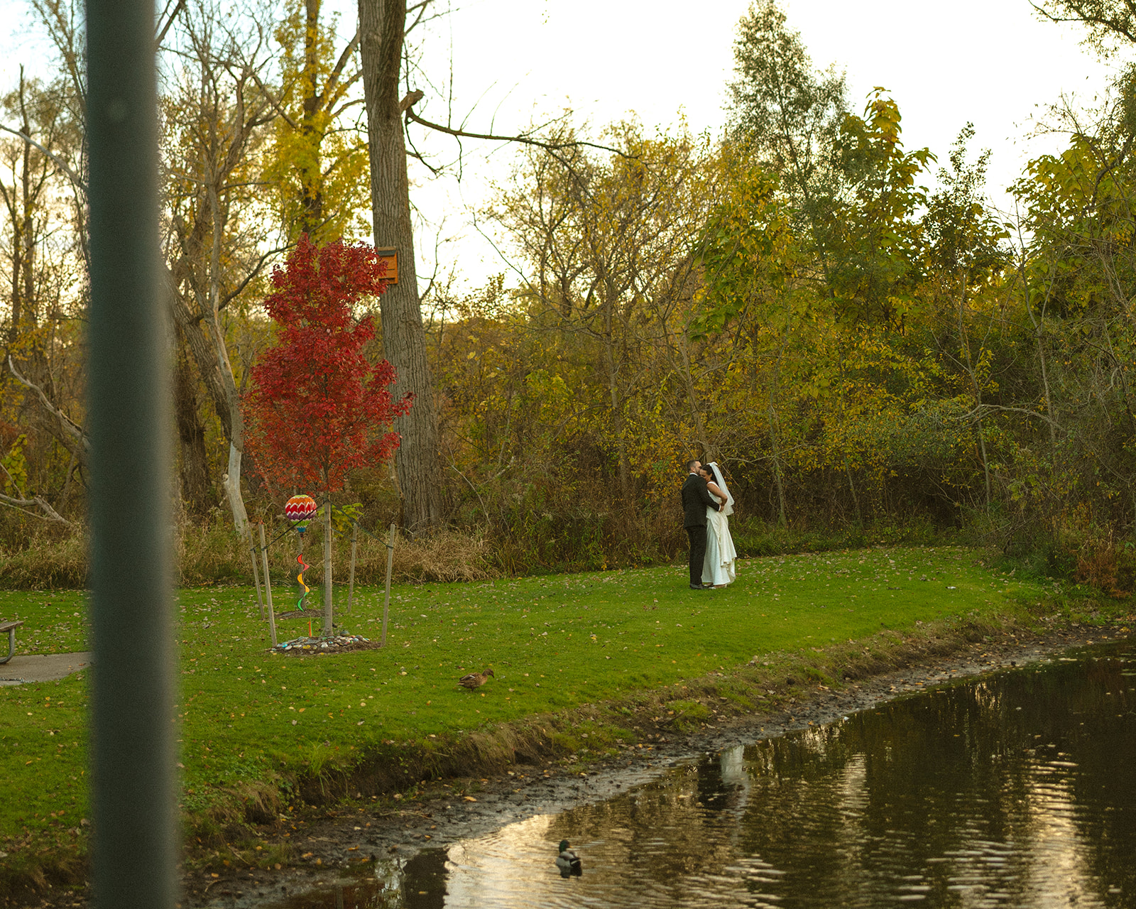 Bride and groom embracing near water at sunset during portraits at a Clarkston Michigan wedding.