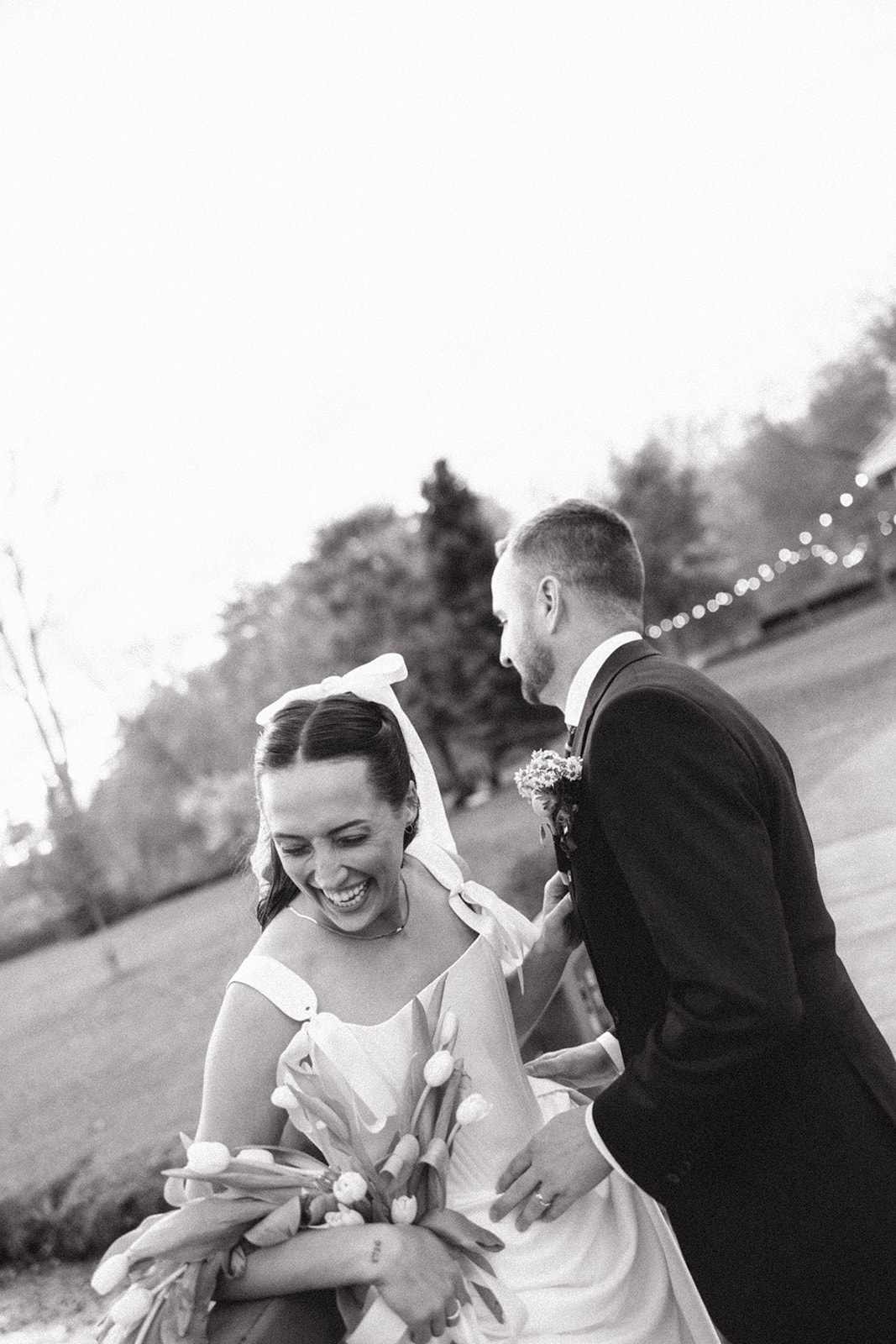 Black and white candid photo of a bride and groom laughing during their outdoor portraits. 