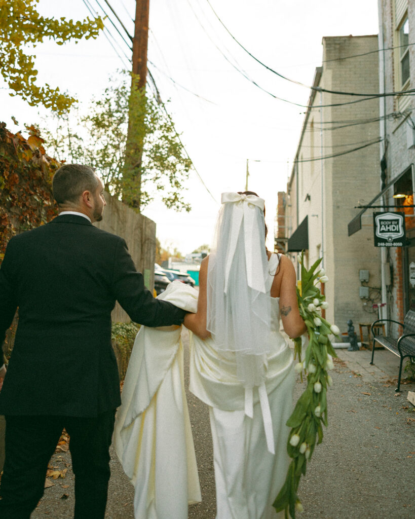 Bride and groom walking together down an alleyway. 