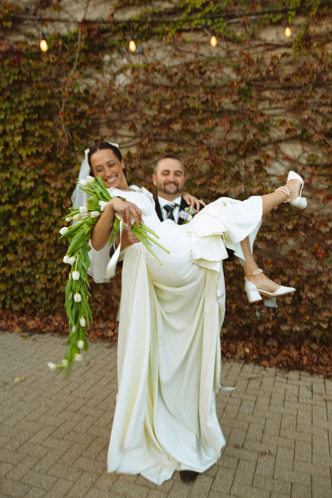 Groom lifting his bride in his arms during their Clarkston, Michigan wedding portraits. 